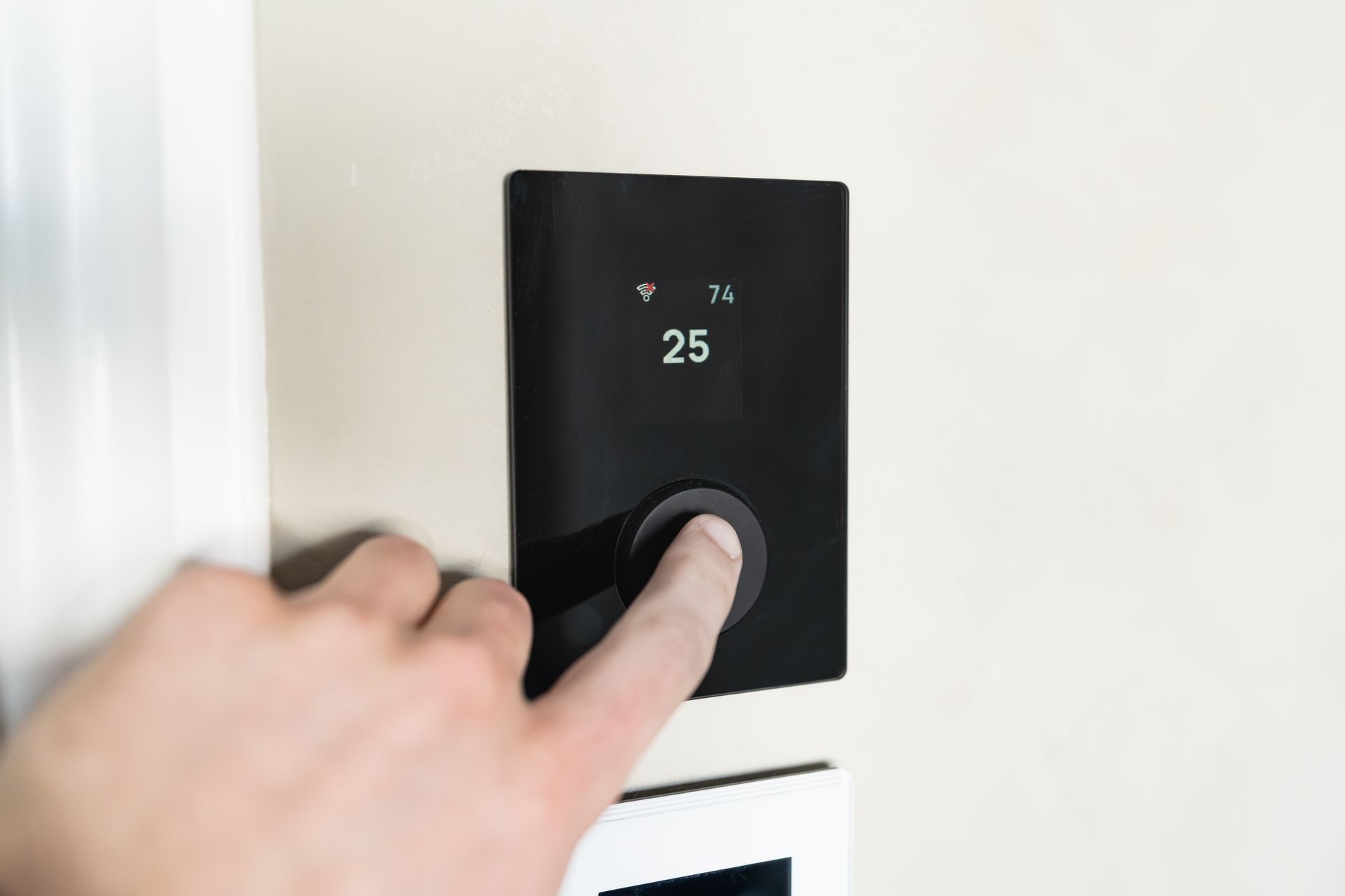Hand stellt ein modernes Heizungsthermostat ein.